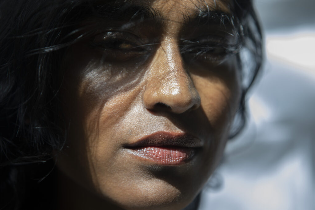 Close-up portrait of Barathy Akkan with windblown hair, looking towards the camera in natural sunlight.