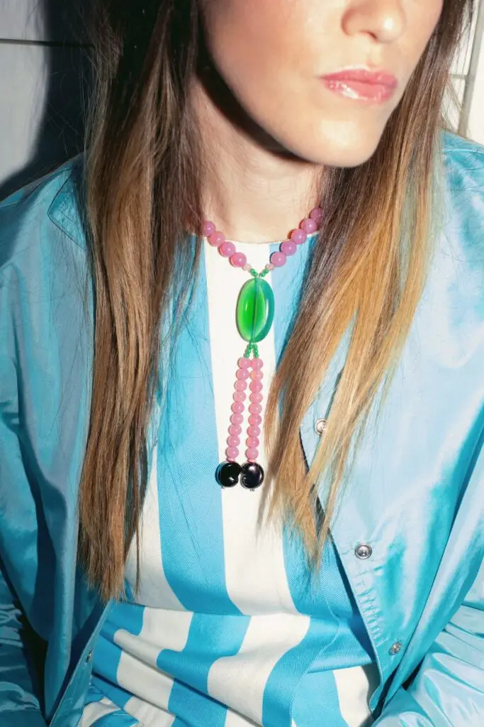 Close-up of Anouck Mutsaerts wearing a colourful beaded necklace with a turquoise jacket and striped top.