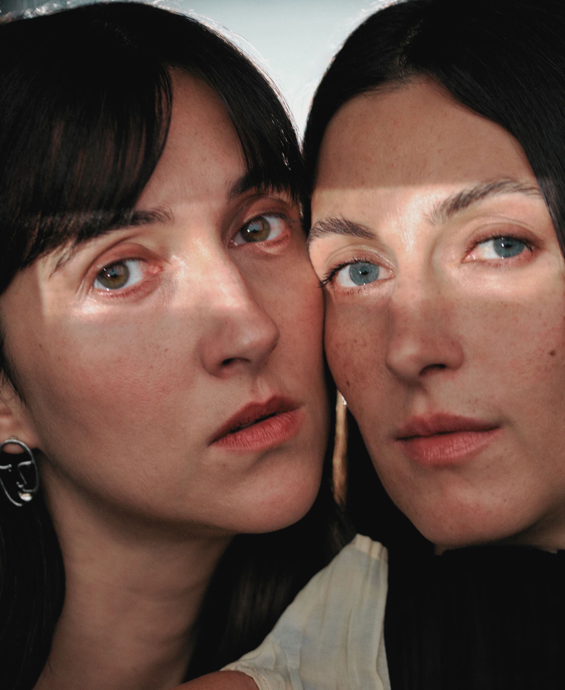 Florine and Kim Nüesch in close-up, their faces side by side as bands of sunlight fall across their eyes.