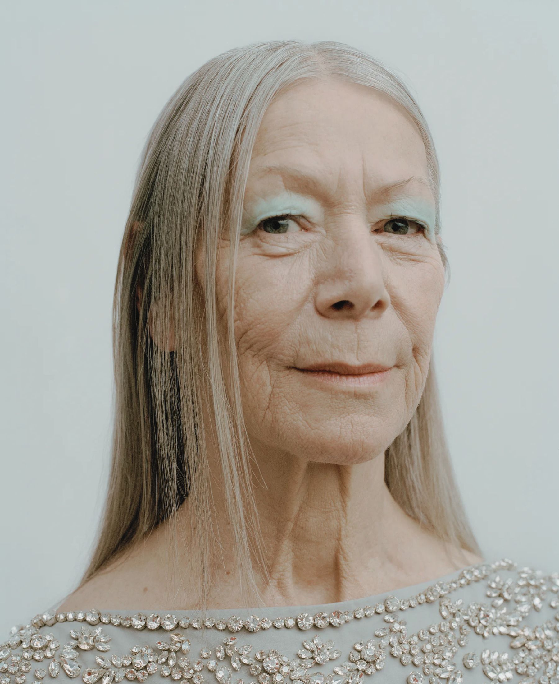 Claudia in close-up, with long silver hair, pale blue eye make-up and an embellished grey dress