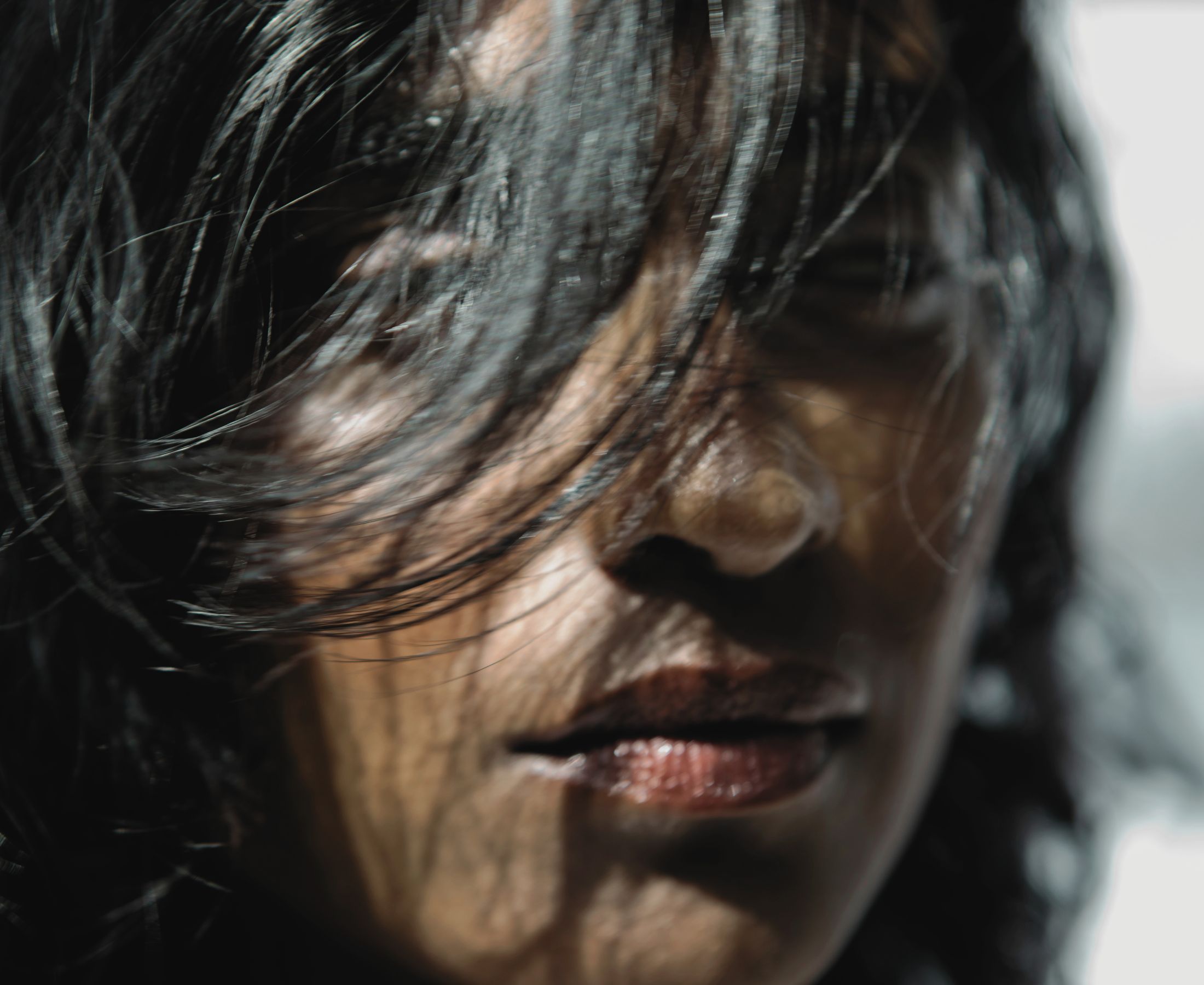 Barathy Akkan in close-up, with strands of dark hair across her face and sunlight catching her skin