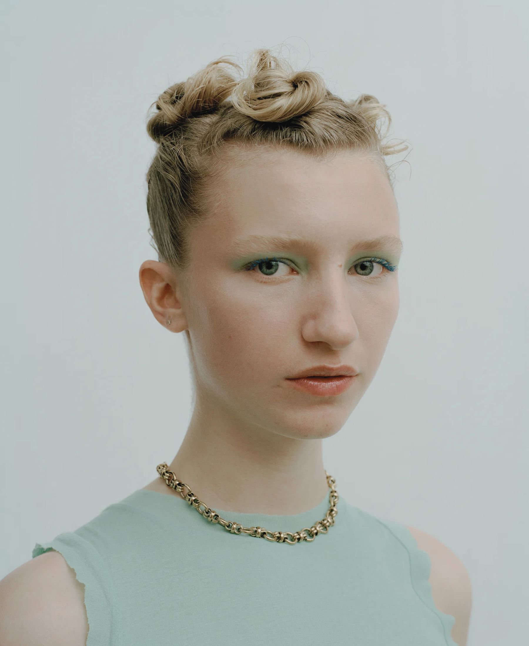 Iris in close-up, with sculpted blonde curls, vivid blue mascara and a pale mint shirt.
