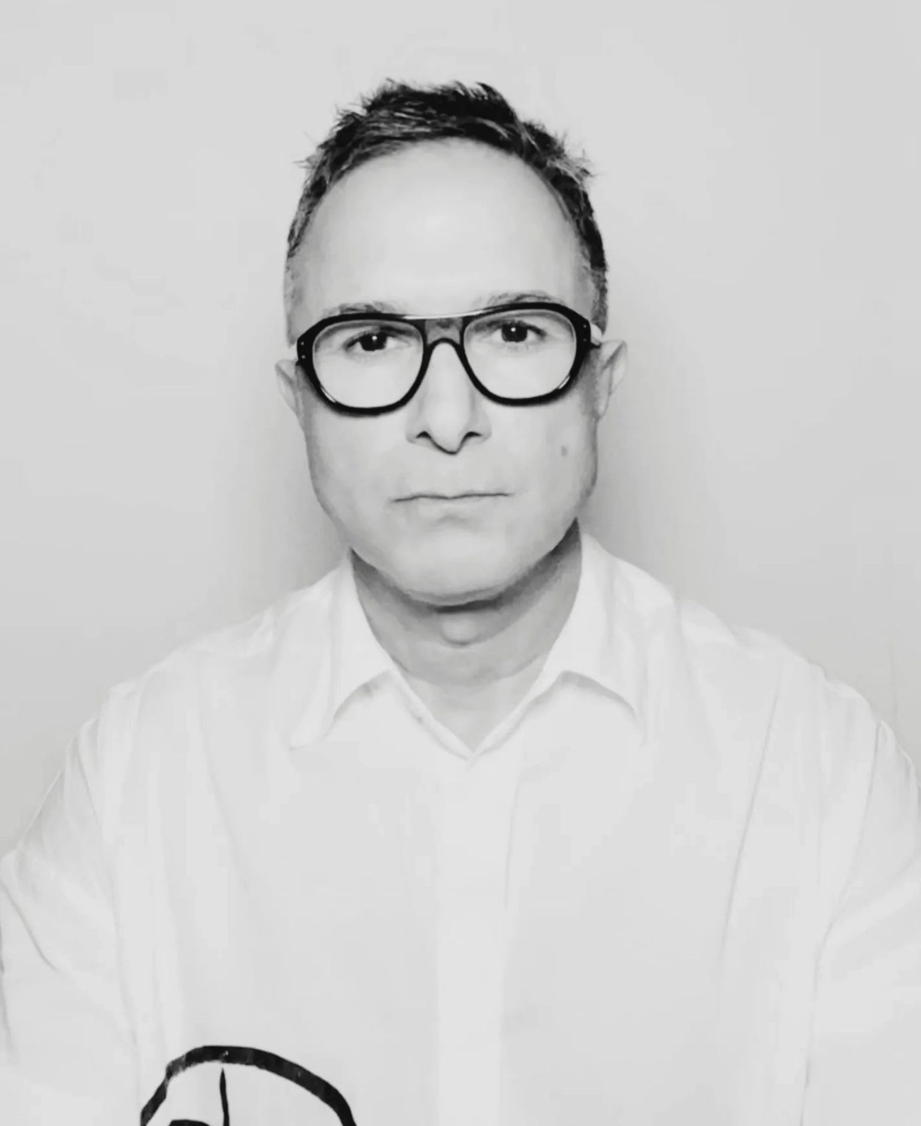 Black-and-white portrait of Matin Maulawizada wearing oversized dark-rimmed glasses and a crisp white shirt.