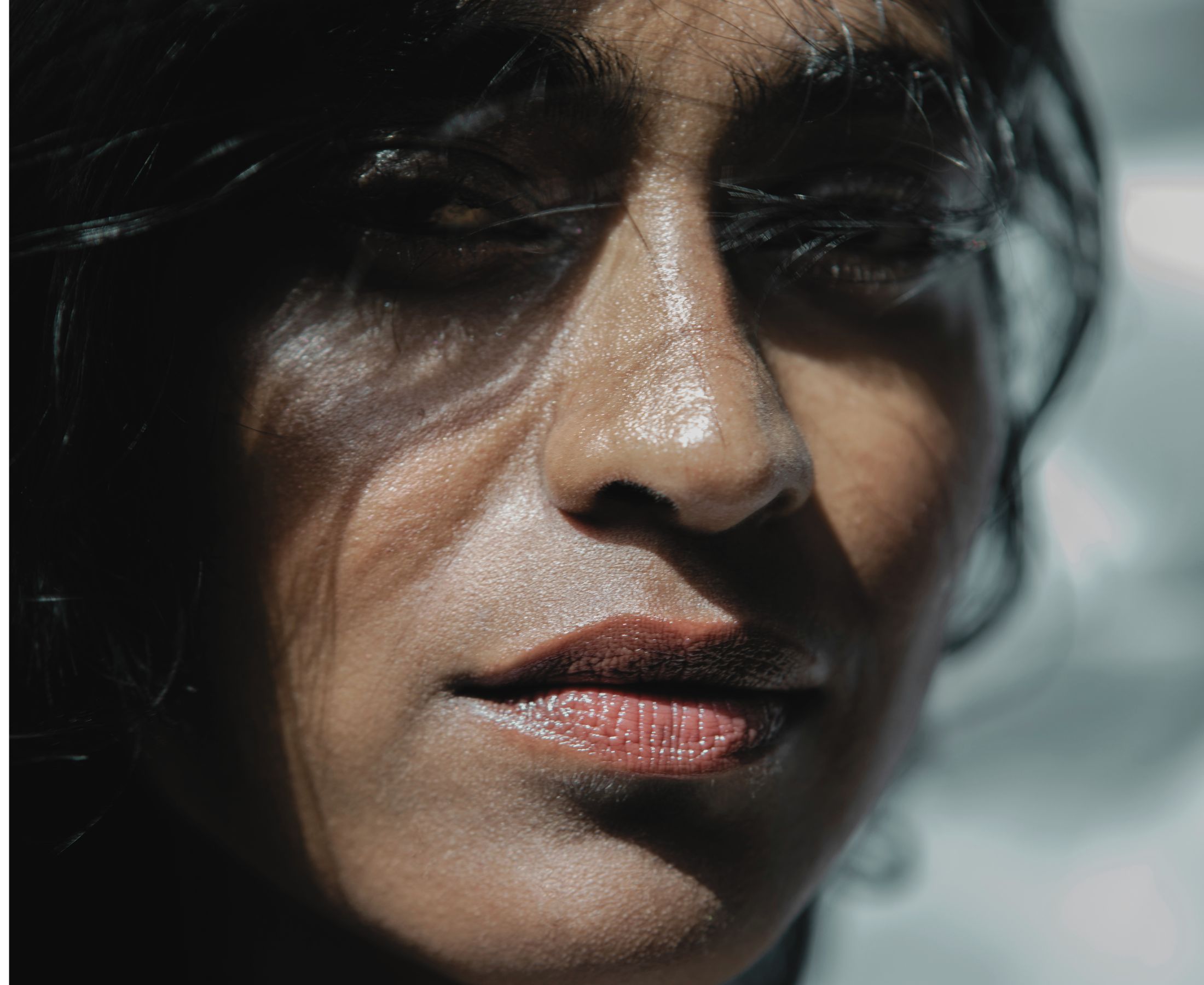 Barathy Akkan in close-up, with loose hair crossing her face as the light shifts across her skin.