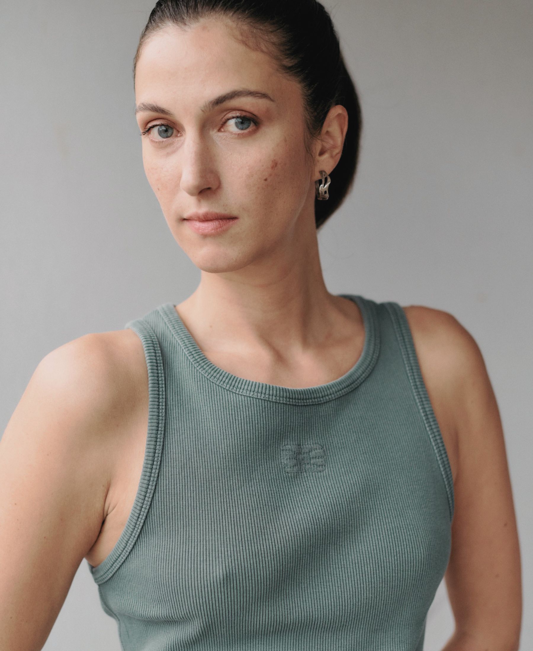 Portrait of Florine Nüesch in a grey sleeveless top, photographed against a quiet neutral background.