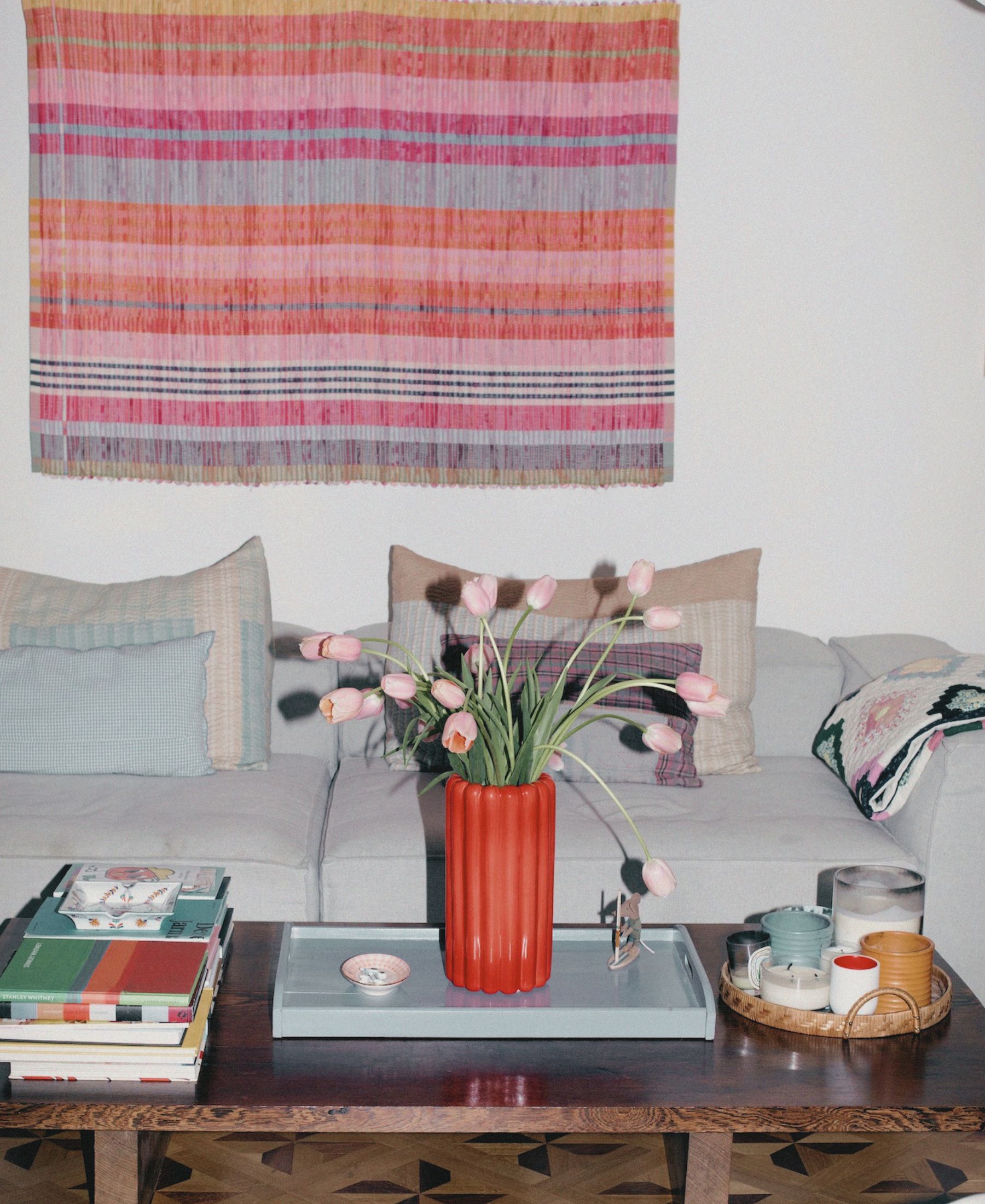 Eine farbenfrohe Ecke in Anouck Mutsaerts’ Zuhause mit Büchern, Blumen, Textilien und persönlichen Gegenständen.